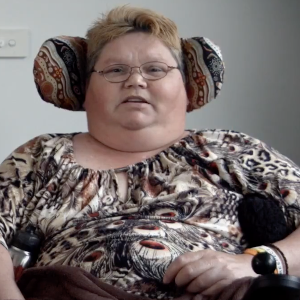 Woman sitting on a wheelchair wearing eyeglasses