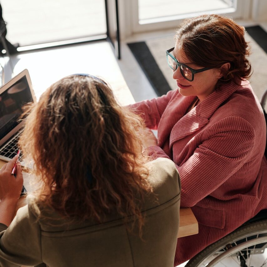 two ladies talking on her wheelchair wearing her eyeglasses