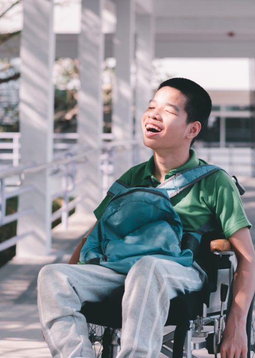 a smiling face child on the wheelchair with a backpack